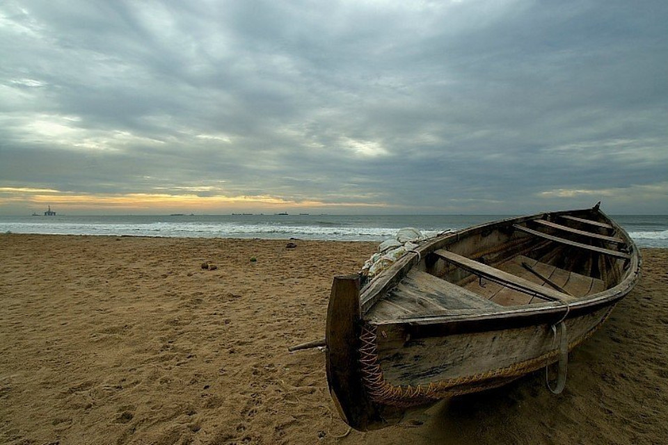 a fisherman boat laying on the shore of yarada beach in the evening