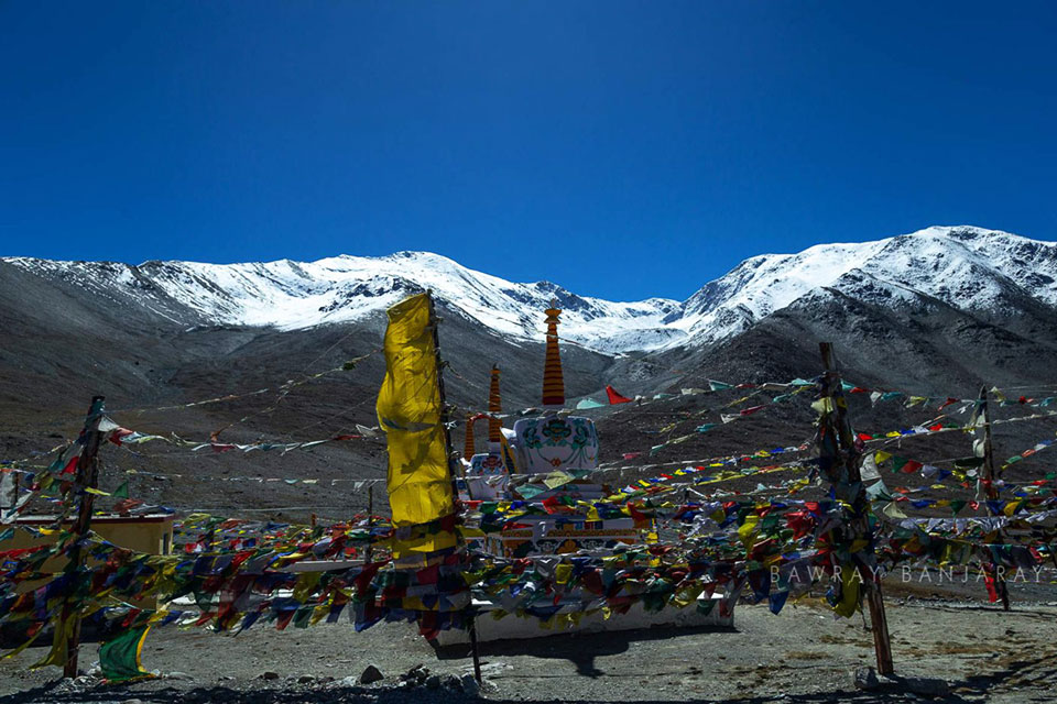 budhhist stupa and flags at kunzum village with snowy himalayas in the background