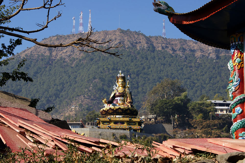 guru rinpoche statue as viewed from the lake with himalayas in the background